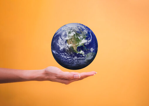 Woman hand holding flying earth global isolated on yellow backgrounds, save and earth day concept, Elements of this image furnished by NASA.