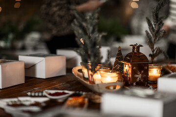 white boxes with cupcakes, cups with decor and spices on a wooden table with candles and a fir tree, preparation of a women's Christmas master class