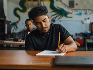 Obraz premium Eye level image of a Native boy writing on paper in school