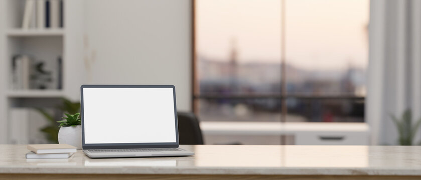 Laptop mockup and copy space on modern white tabletop over blurred office in background.