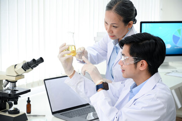 Senior female medical supervisor testing a medical liquid with a young male medical technician