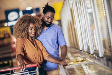African American couple with trolley purchasing groceries at mall