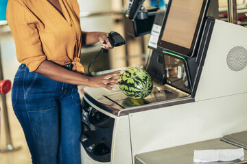 African American Woman buying food at grocery store or supermarket self-checkout - obrazy, fototapety, plakaty