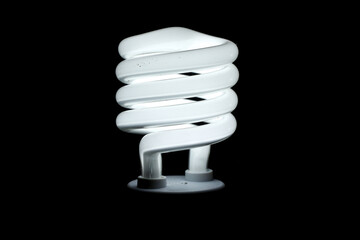 Glowing spiral light bulb isolated on dark background. Eco energy saving light bulb concept