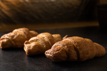 Close-up of golden croissants on a dark background. French pastries. Rustic breakfast.