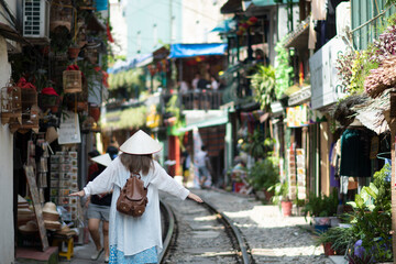 Woman traveller walk around railway paths which go through residential area in Hanoi city. Hanoi Train Street is a famous tourist destination.