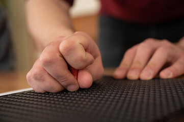 A man uses a special stencil and stylus to write a letter in braille. 