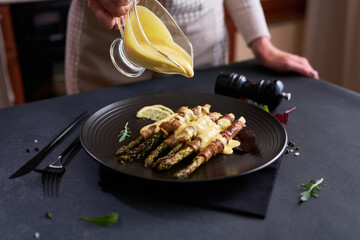baked aspargus covered with bacon on a black ceramic plate