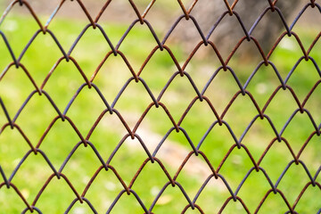 Fototapeta premium iron chain link fence against green meadow