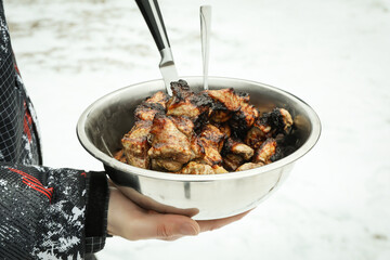 Man holds metal bowl with tasty shashlik