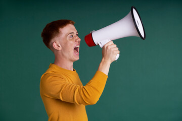 Caucasian red head teenager screaming through a megaphone