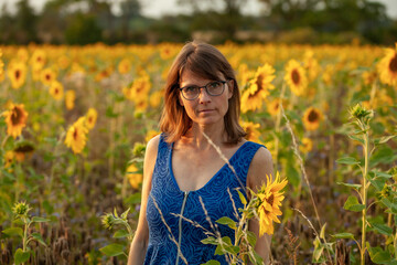 Naklejka na ściany i meble Portrait einer hübschen Frau mit Sonnenblumen im Hintergrund