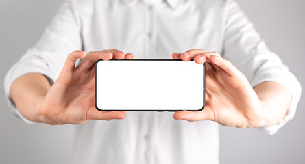Woman holding phone mockup in horizontal position. Female using smartphone for showing video,...