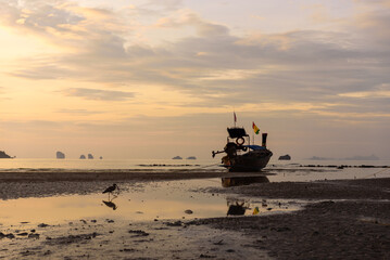 View of beautiful sunrise sky with long tail boat at Krabi beach, fishing boat in the sea