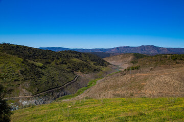 Paisaje de valles y montañas con pequeño embalse y rutas de senderismo