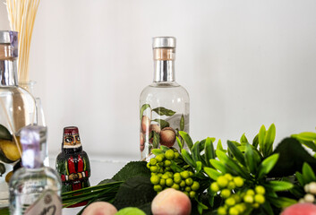 still life with fruits and flowers and a national doll against the background of bottles of fruit...