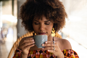 Young African woman smelling coffee cup