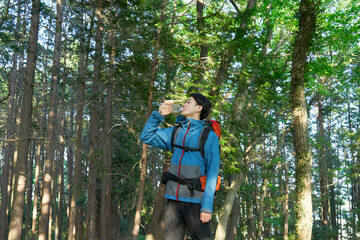 Fototapeta premium ペットボトルの水を飲んで水分補給する登山者