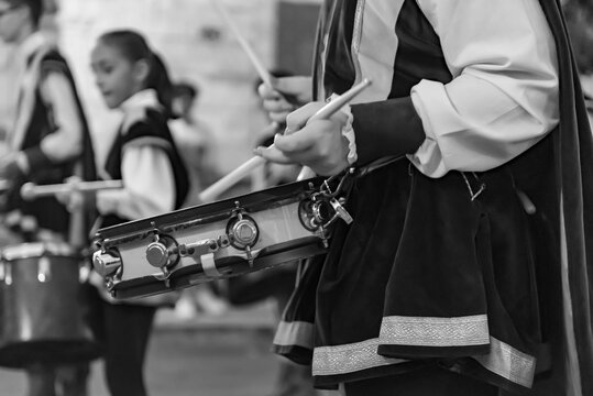 black and white close-up of a musician playing the snare drum dressed in medieval clothing during a historical parade - Powered by Adobe
