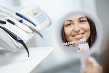 Reflection of a woman with a healthy smile in a dental mirror