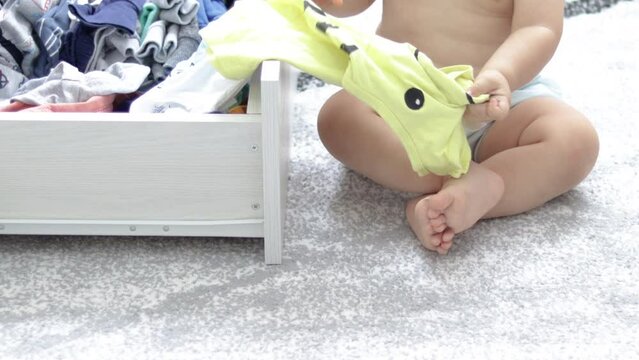 cute baby boy playing on the floor gray carpet taking out the clothes from drawer or get up, crawling around.toddler wear washable cloth diaper,eco alternative.morning situation,maternity concept