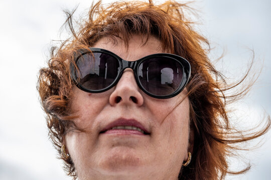 a woman in dark sunglasses with a reflection of a gazebo in a gorge in them