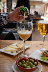 Lunch with cold beer in Spanish outdoor cafe, tapas bowl with green olives and Spanish cheese manchego with nuts