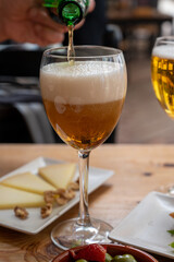 Lunch with cold beer in Spanish outdoor cafe, tapas bowl with green olives and Spanish cheese manchego with nuts