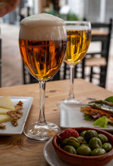Lunch with cold beer in Spanish outdoor cafe, tapas bowl with green olives and Spanish cheese manchego with nuts
