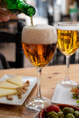 Lunch with cold beer in Spanish outdoor cafe, tapas bowl with green olives and Spanish cheese manchego with nuts