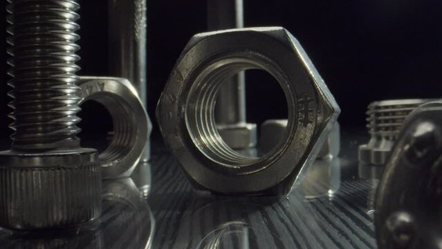 Set of bolts nuts and washer rings on table in dark studio closeup. New metal fastening equipment in hardware store