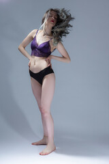 Full Length Portrait of Sensual Girl With Long Hair in Violet Nightie and Black Panties Demonstrating Long Hair and Posing on Gray Background as Fashion Style Portrait.