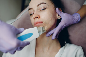 Woman receiving cleansing therapy with a professional ultrasonic equipment in cosmetology beauty...