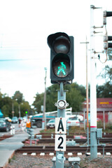 Traffic light with green man allowing railroad crossing, safe pedestrian crossing over railroad tracks