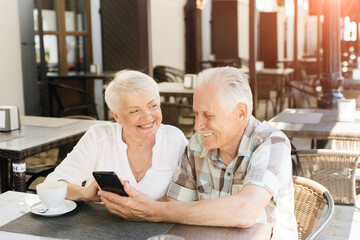 Senior couple using mobile phone in a cafe