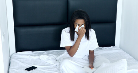 Sick young woman cough sneeze rest in bed at home blowing nose suffer from fever, ill millennial girl feel bad weak struggle with flu, having runny nose.