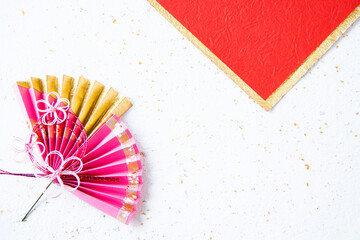 日本の正月　華やかな水引飾りのついた扇のデザイン（赤と白と金色の和紙の背景）