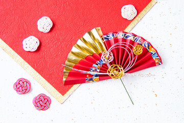 日本の正月　華やかな水引飾りのついた扇のデザイン（赤と白と金色の和紙の背景）