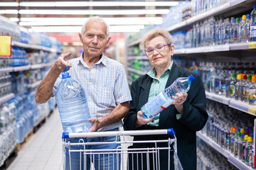mature european spouses selects bottled water in the department of supermarket