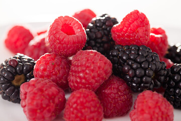 handful of raspberry and blackberry berries on white background