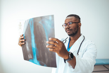 Afrian American adult male doctor looking at x-ray. Doctor examining a lung radiography. Doctor...