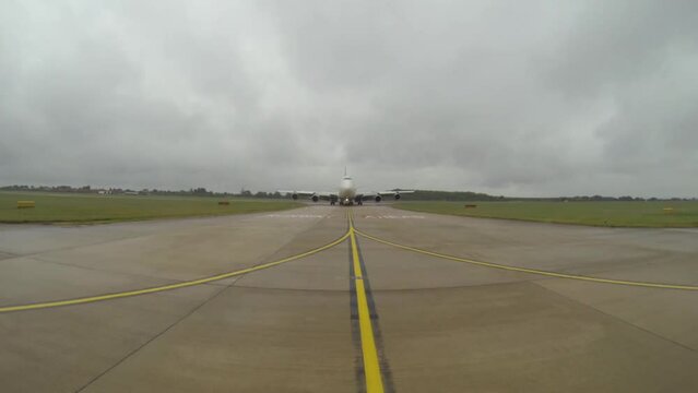 A vehicle drives in front of a large aircraft to give it guidance on where to go and where to park.