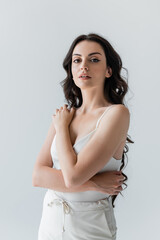 Long haired model in white clothes looking at camera isolated on grey.