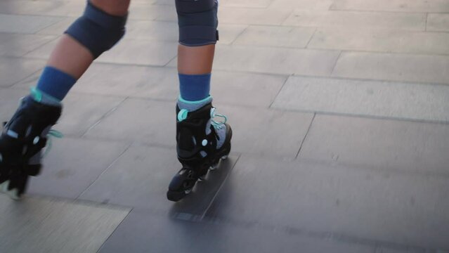 Close-up of legs roller skating in city park. Young girl learning how to roller skate. Active lifestyle concept.