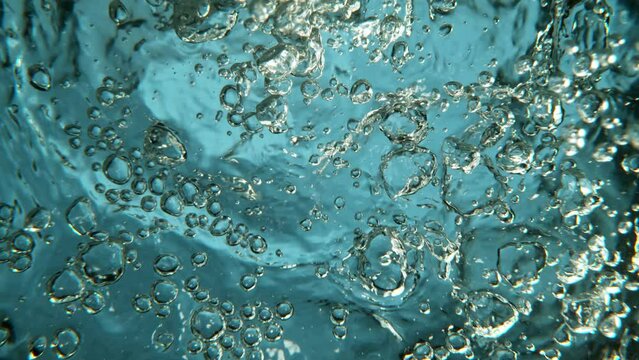 Super slow motion of water surface with bubbles on light blue background. Filmed on high speed cinema camera, 1000 fps.