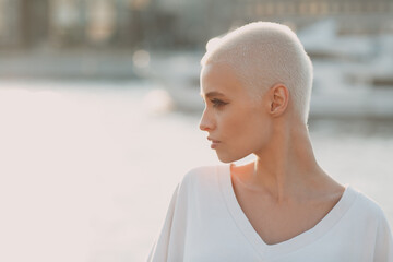 Portrait profile of young smiling millenial european short haired woman. Beautiful happy blonde girl outdoor. Summer fashion female clothing.