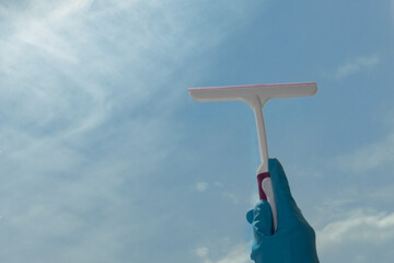 cleaning and housekeeping, wash window service, hand in glove with scraper washes glass overlooking blue sky