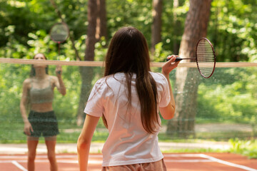 teenager sport outside in summer,badminton in park, two girls players play with rackets and...