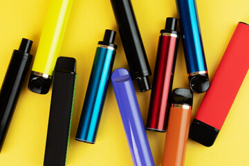 vape, multicolored electronic cigarettes for smoking with different flavors on a yellow background