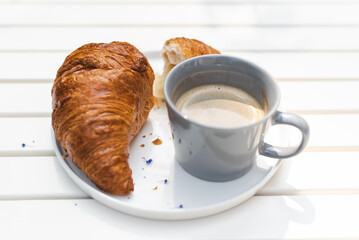Crispy croissant and fresh coffee at the outdoor cafe. Breakfast, lunch concept.